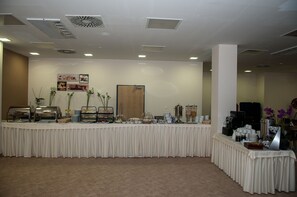 Ein reichhaltiges Buffet mit verschiedenen Speisenstationen, darunter eine Kaffeemaschine und eine Obstauslage.