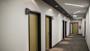 A long, narrow hallway with doors on one side and a carpeted floor. - Hotel Meeting (Torun)