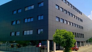 A modern building with a flat facade, multiple windows, and a no parking sign. - Hotel Meeting (Torun)