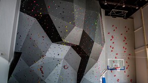 A climbing wall with various colored holds and a basketball hoop. - Hotel Meeting (Torun)