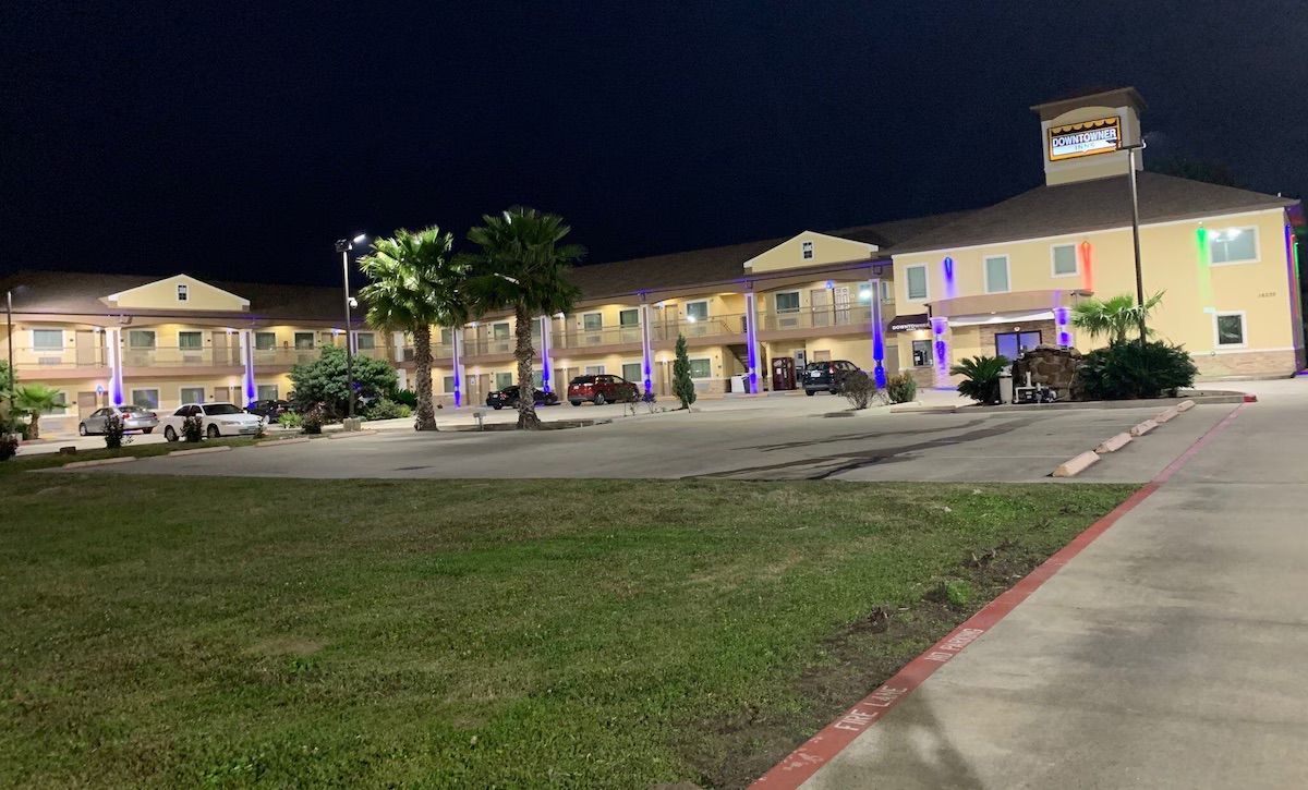 A multi-story hotel with a parking lot, palm trees, and a sign indicating it is a Courtyard Inn.