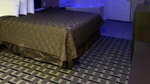 A hotel room with a large bed, a bathroom with a bathtub, and a door.