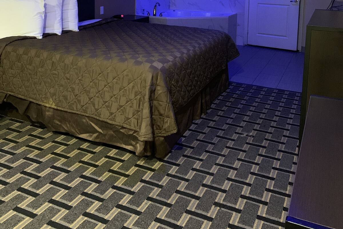 Ein Hotelzimmer mit einem großen Bett, einem Badezimmer mit einer Badewanne und einer Tür.