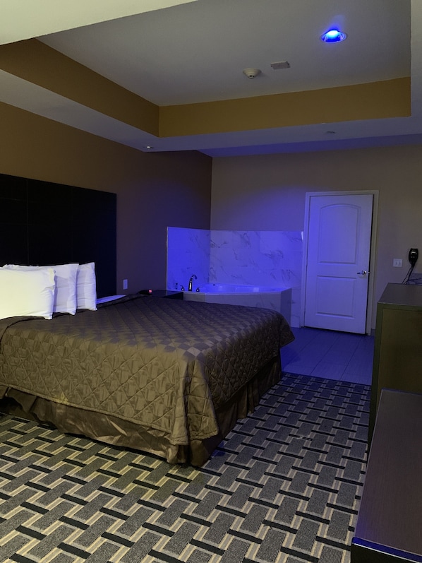 Une chambre d’hôtel avec un grand lit, une salle de bain avec une baignoire et une porte.