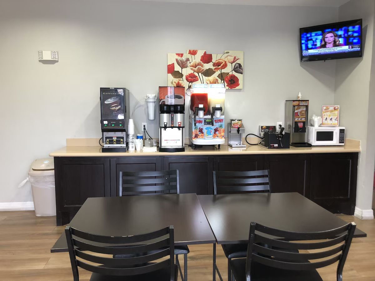 A kitchenette with a coffee maker, microwave, and a TV mounted on the wall.