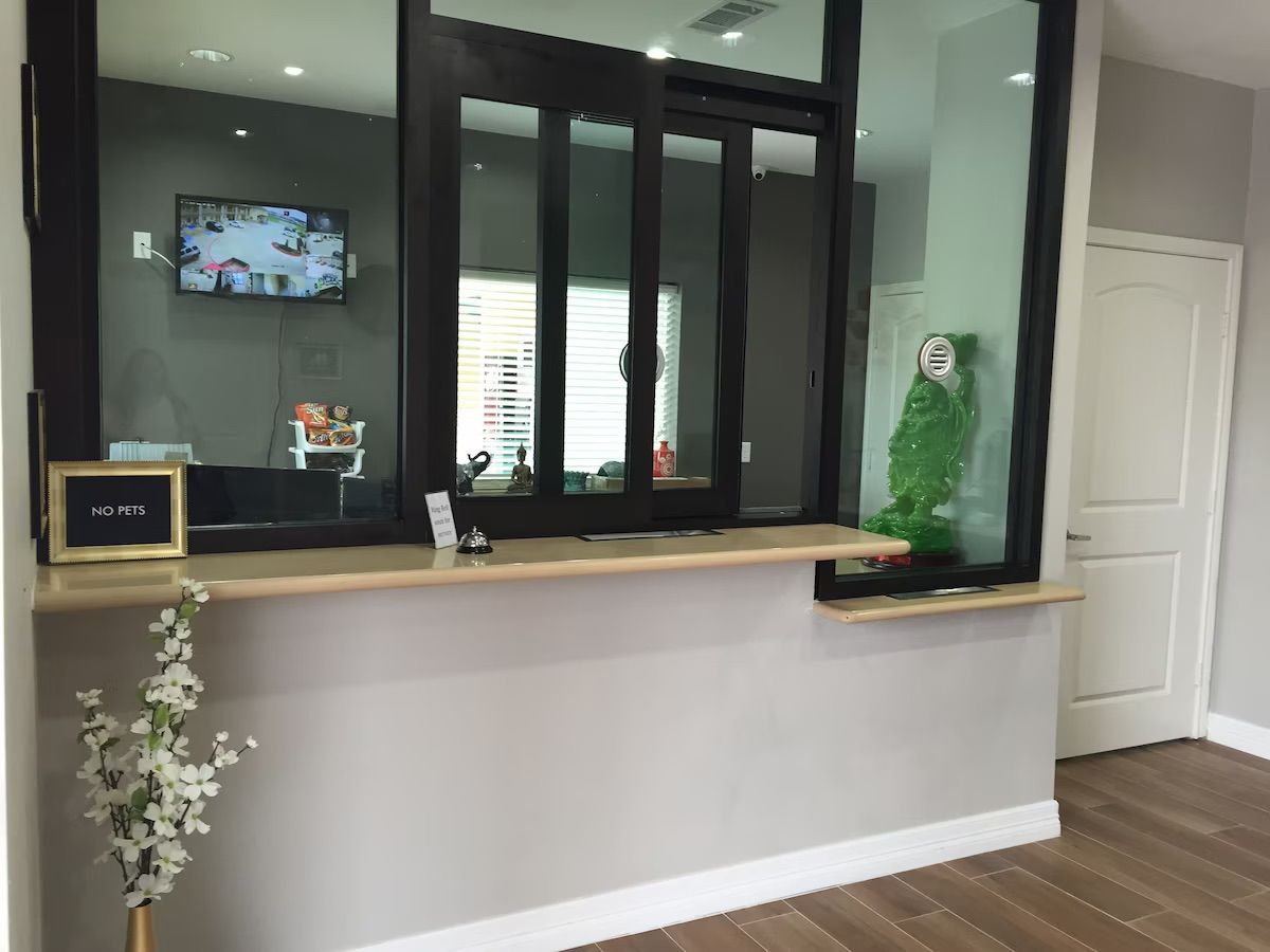 A reception desk with a 'NO PETS' sign, a television mounted on the wall, and a small plant on the counter.
