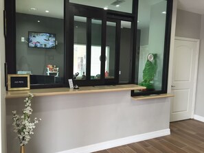 A reception desk with a 'NO PETS' sign, a television mounted on the wall, and a small plant on the counter. - Downtowner Inn (Houston)