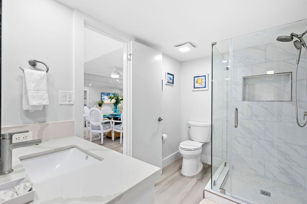 A modern bathroom with a large sink, toilet, and glass-enclosed shower.