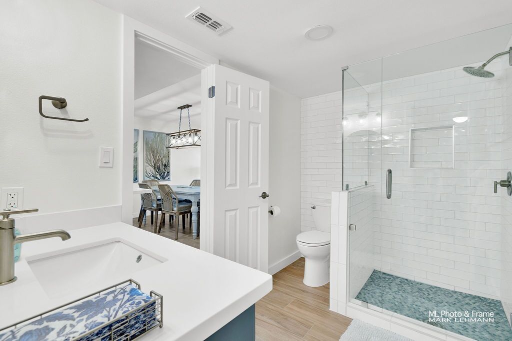 Un baño moderno con lavamanos blanco, inodoro y ducha con mampara de vidrio.