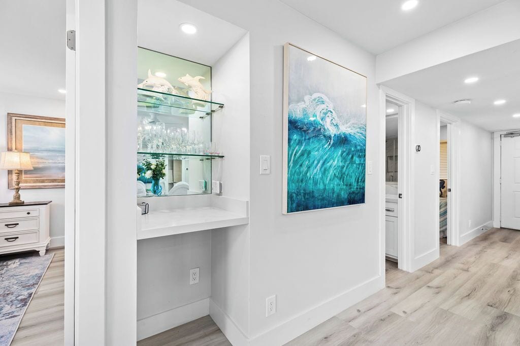 Une salle de bain moderne avec une étagère en verre, un grand tableau abstrait et un plancher en bois.
