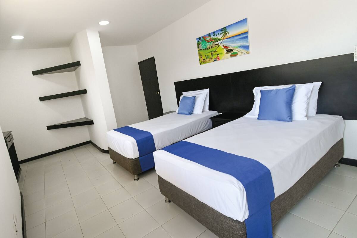 Ein Hotelzimmer mit zwei Betten, einem Bild an der Wand und einem schwarzen Kopfteil.