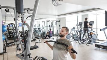 Un gimnasio con varios equipos de ejercicio, incluyendo cintas de correr y máquinas de pesas.