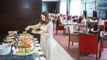 Disposição de buffet numa área de refeições com várias mesas e cadeiras.