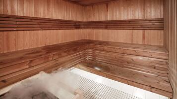 A sauna with wooden walls and benches, steam visible, and a tiled floor.