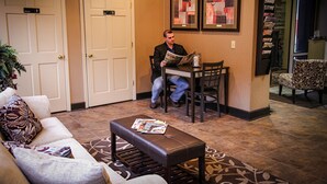 A hotel lobby with a reception desk, a waiting area with a sofa and a bench, and a door marked "Women". - The Landmark Hotel (Pikeville)