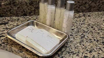 A tray with a bar of soap and four bottles of lotion on a granite countertop.