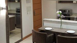 Una cocina moderna con microondas, horno y comedor con mesa y sillas.