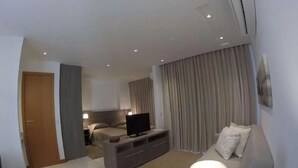 Una habitación de hotel moderna con una cama, un televisor, un sofá y una lámpara.
