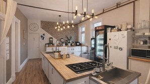 Una cocina con una isla central, un refrigerador, un lavabo y un reloj en la pared.