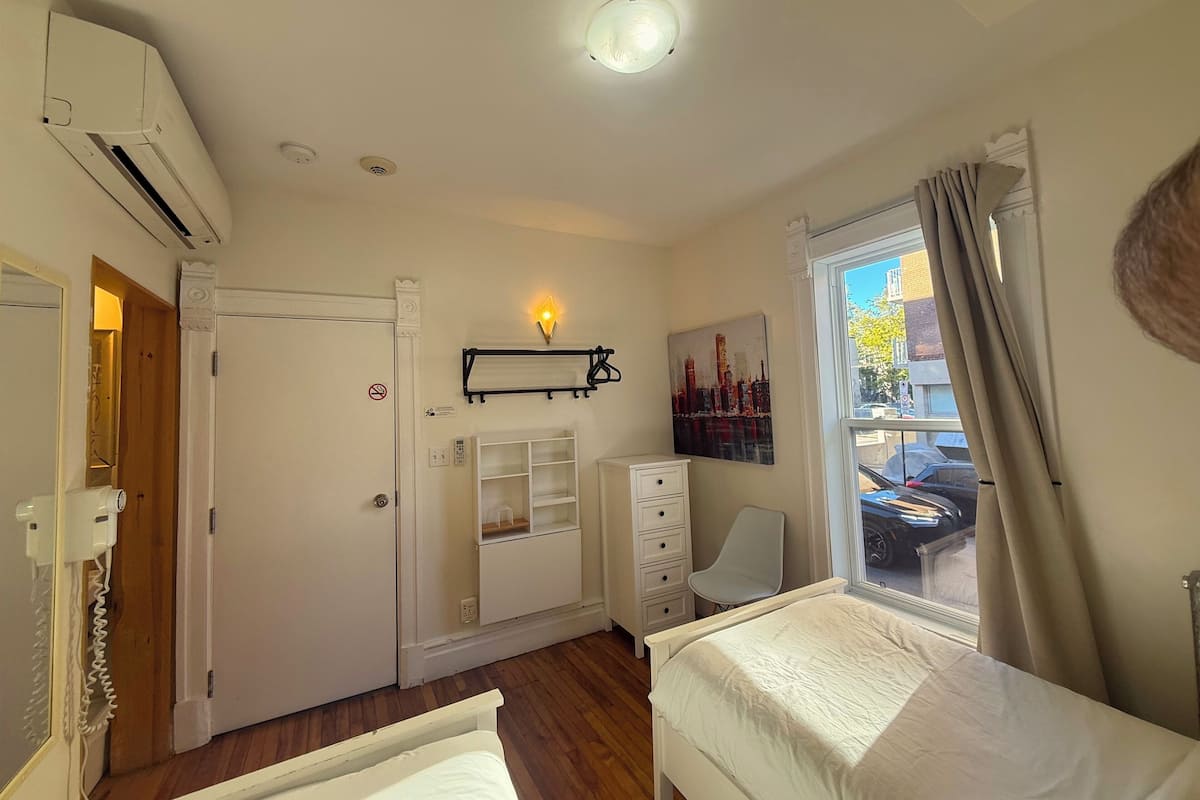 A bedroom with a bed, a desk, a chair, a wardrobe, and a window with curtains.
