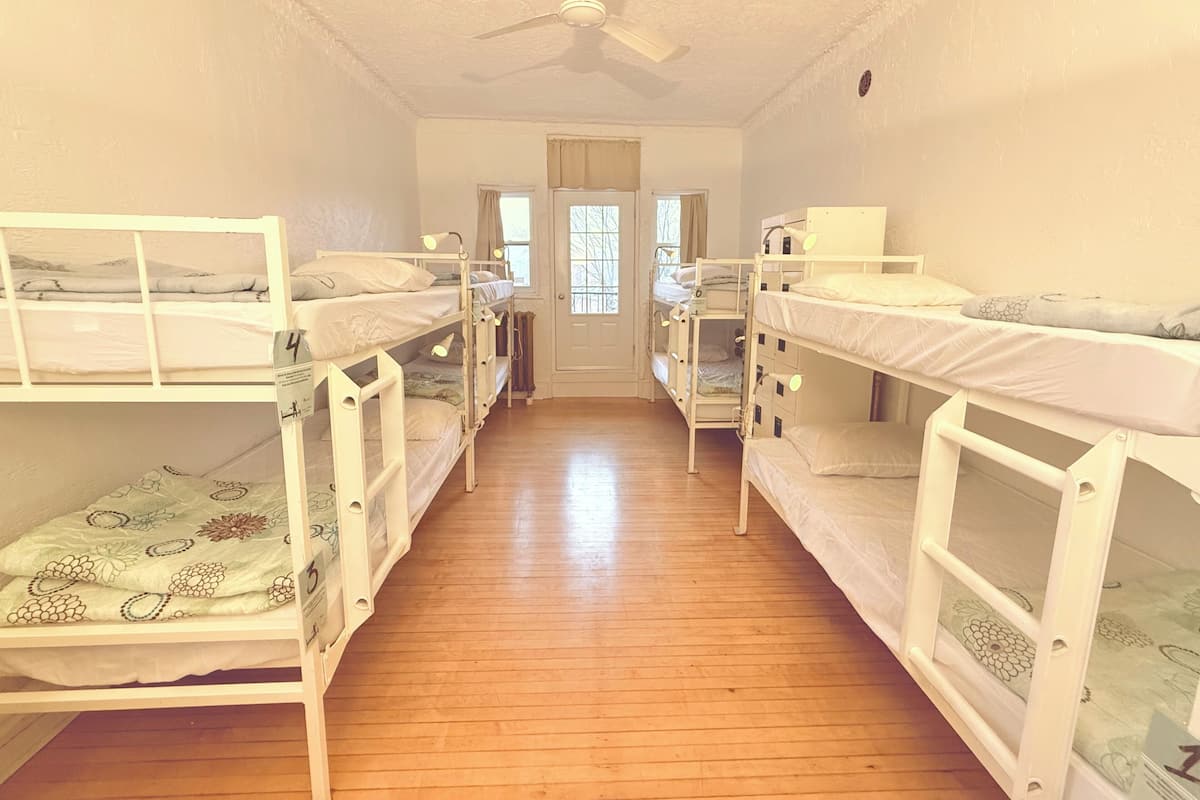 A room with bunk beds, wooden flooring, a ceiling fan, and a door with windows.