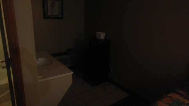 A dimly lit bathroom with a white sink, a mirror, and a toilet. - Ashland Inn (Ashland)
