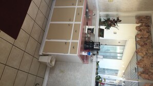 A room with a tiled floor, a white door, a beige wall with a window, and a small plant on the windowsill. - Ashland Inn (Ashland)