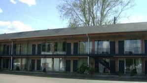A two-story motel with a flat roof, large windows, and a parking lot in front. - Ashland Inn (Ashland)