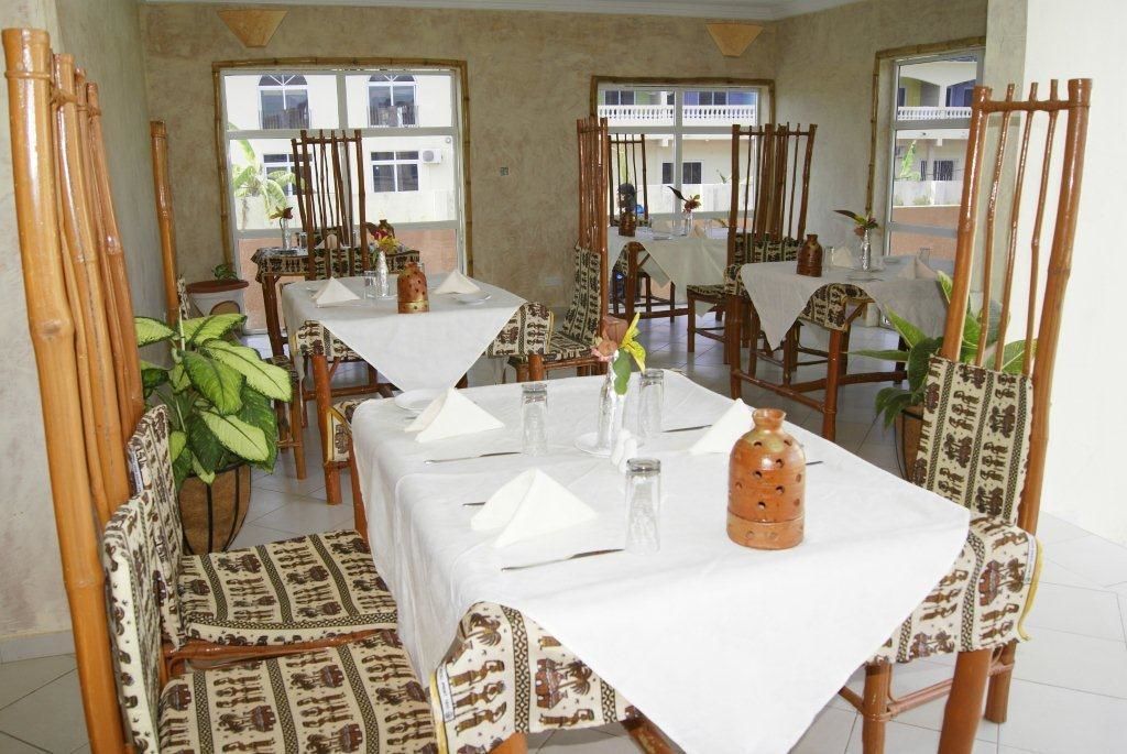 Un comedor con varias mesas y sillas, cada conjunto con manteles blancos y cristalería.