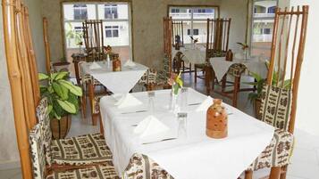 Un comedor con varias mesas y sillas, cada conjunto con manteles blancos y cristalería.