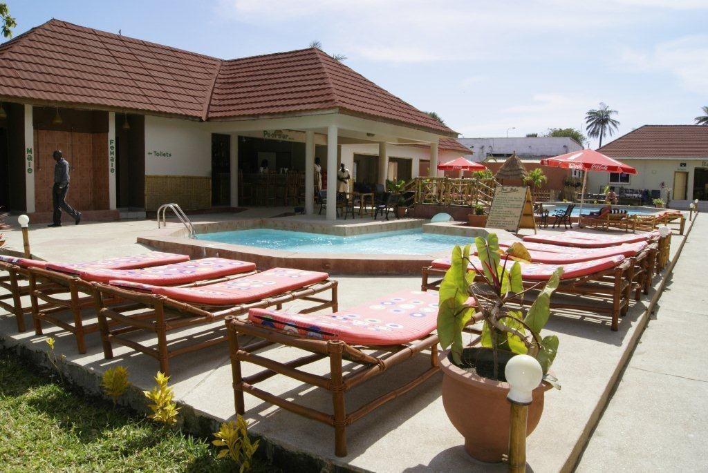 A pool area with lounge chairs and a building with a tiled roof.