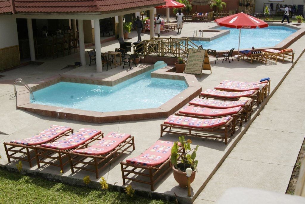 Zona de piscina con sillones de descanso, un bar y un cartel.