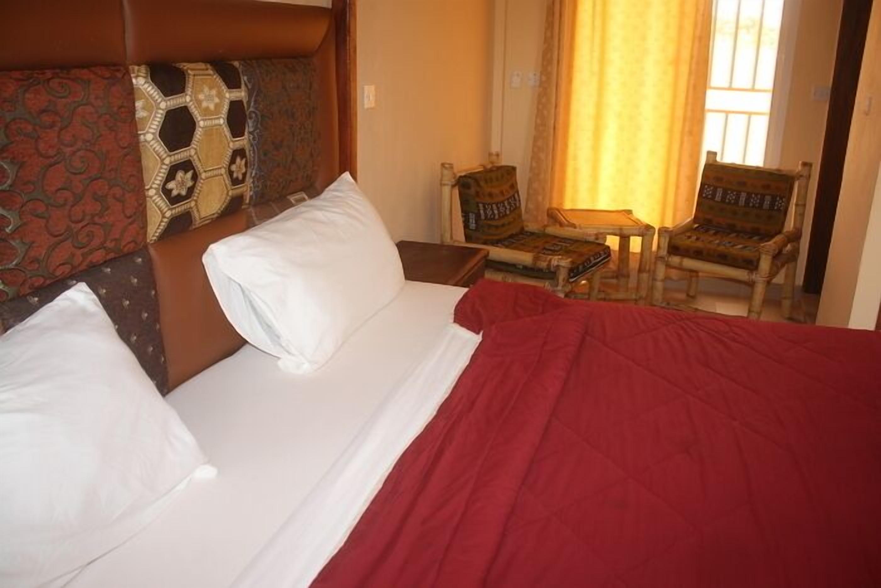 A hotel room with a bed, a chair, and a small table.
