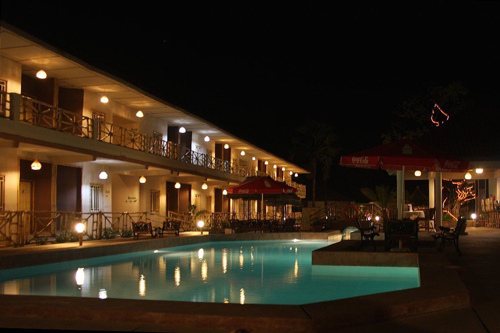 Un hotel con piscina, mobiliario exterior y un pabellón con la marca Coca-Cola.