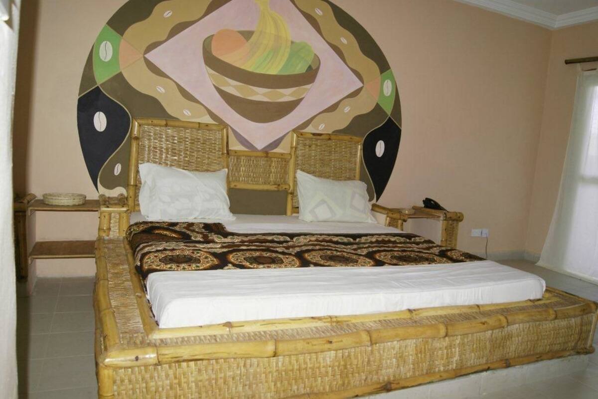 Un lit doté d’une tête de lit et d’un pied de lit en osier, d’un matelas blanc et d’une couverture à motifs.