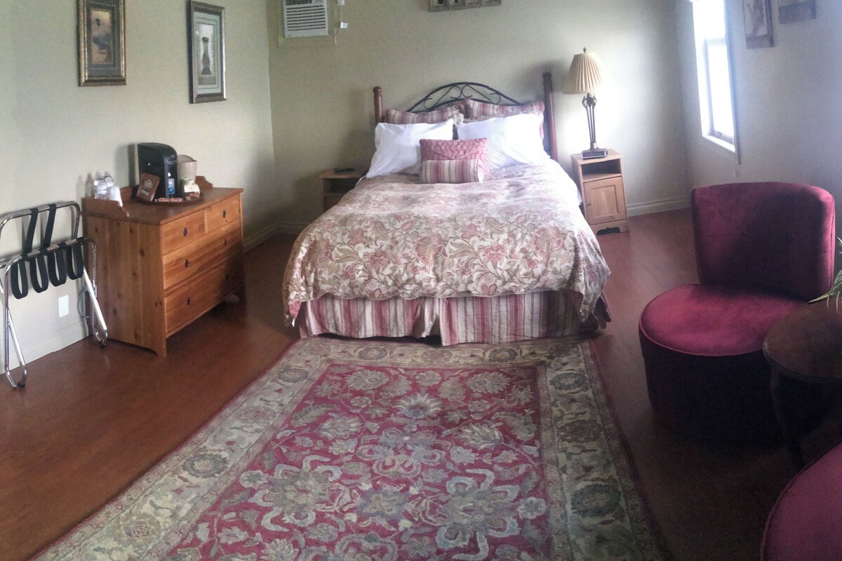Un dormitorio con cama, cómoda, silla y alfombra.