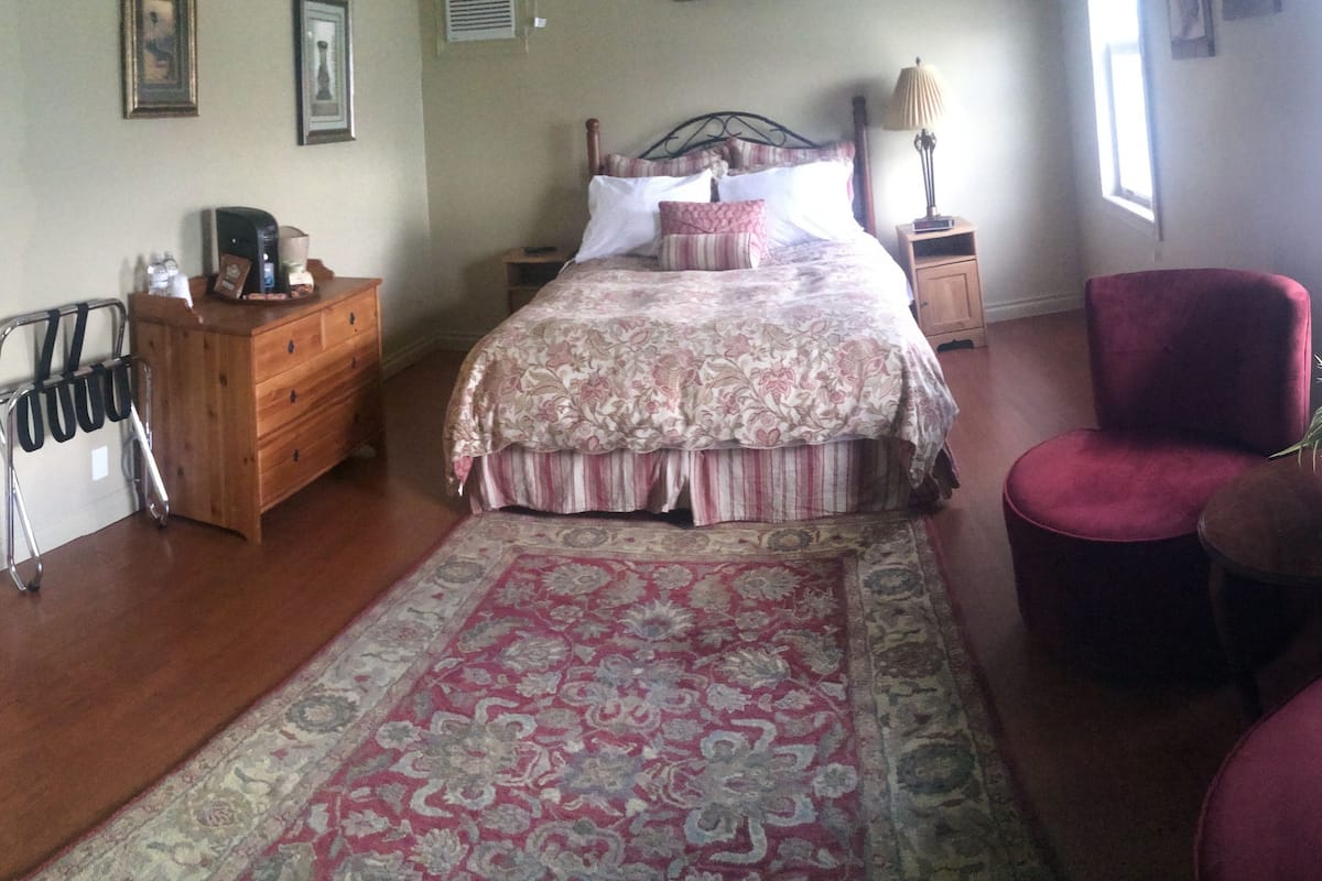 A bedroom with a bed, dresser, chair, and a rug.