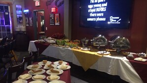 A buffet setup with multiple tables covered in white tablecloths, featuring a variety of dishes including pies and salads. - Dominion Hotel (Minden Hills)