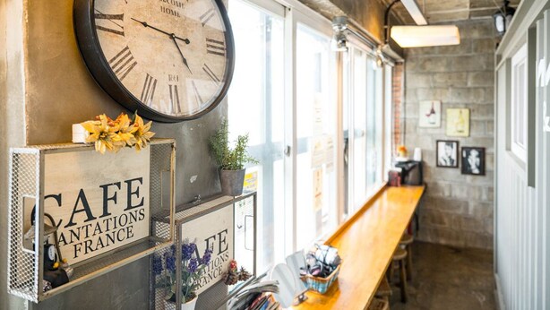 Una cafetería con decoración rústica, que presenta un gran reloj, un banco de madera y un cartel que dice "CAFE ANTIQUATIONS FRANCE".