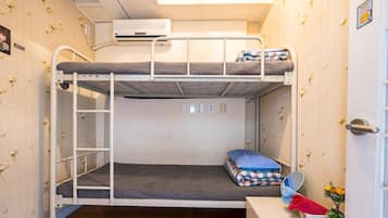 A bunk bed room with a ladder, a small table with a mirror, and a wall-mounted air conditioner.
