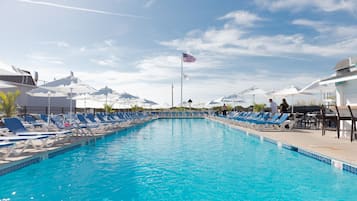 Relax by the rectangular pool surrounded by lounge chairs and umbrellas.