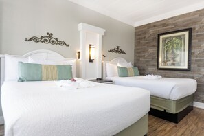A hotel room with two beds, a wooden accent wall, and a framed artwork.
