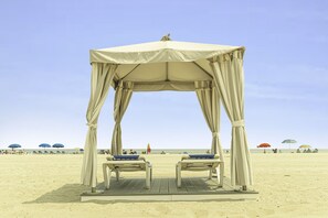 On the beach, white sand, beach cabanas, sun loungers