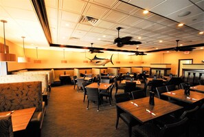 A restaurant with booths and tables, ceiling fans, and pendant lights.