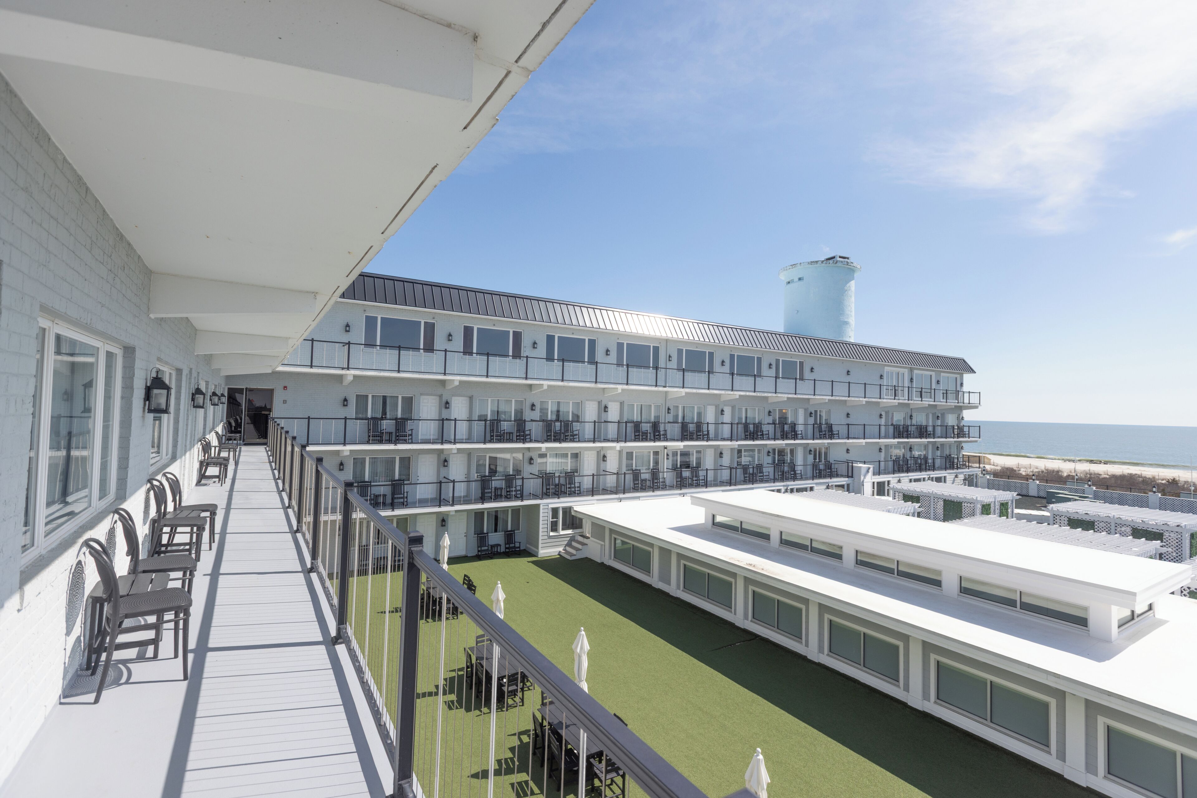 A cruise ship deck with outdoor seating, a pool, and a view of the ocean.