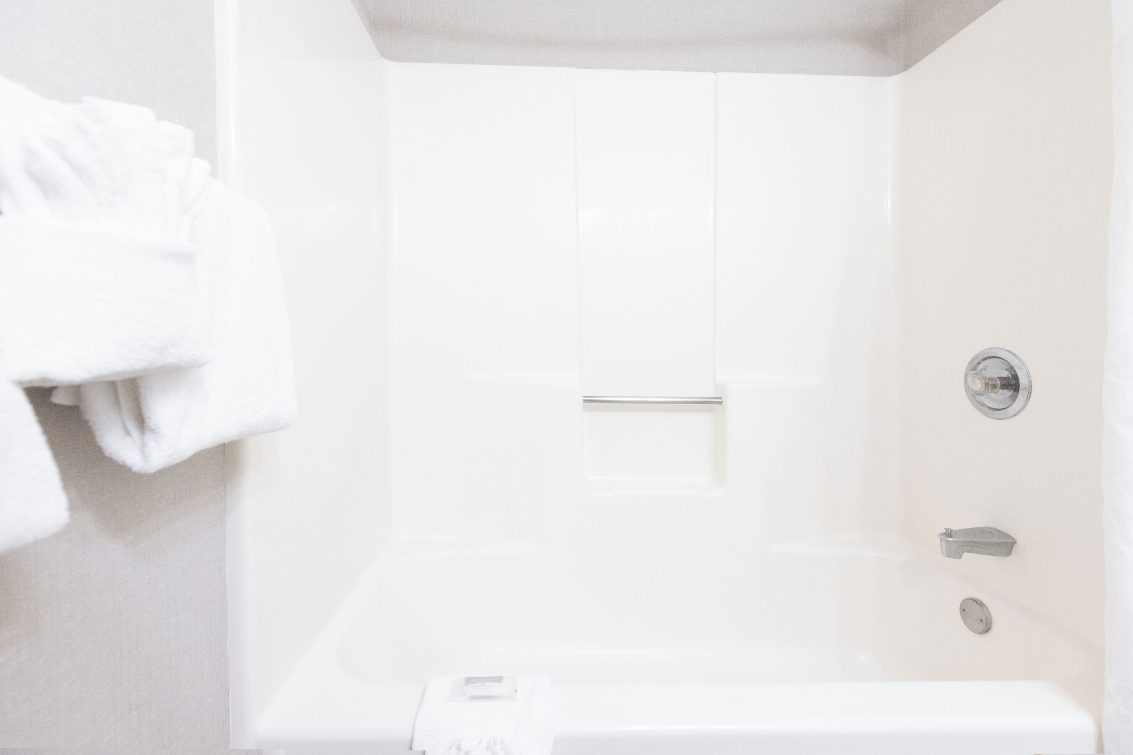 Un baño blanco con bañera, toallero y panel de control de ducha.