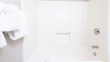 Un baño blanco con bañera, toallero y panel de control de ducha.
