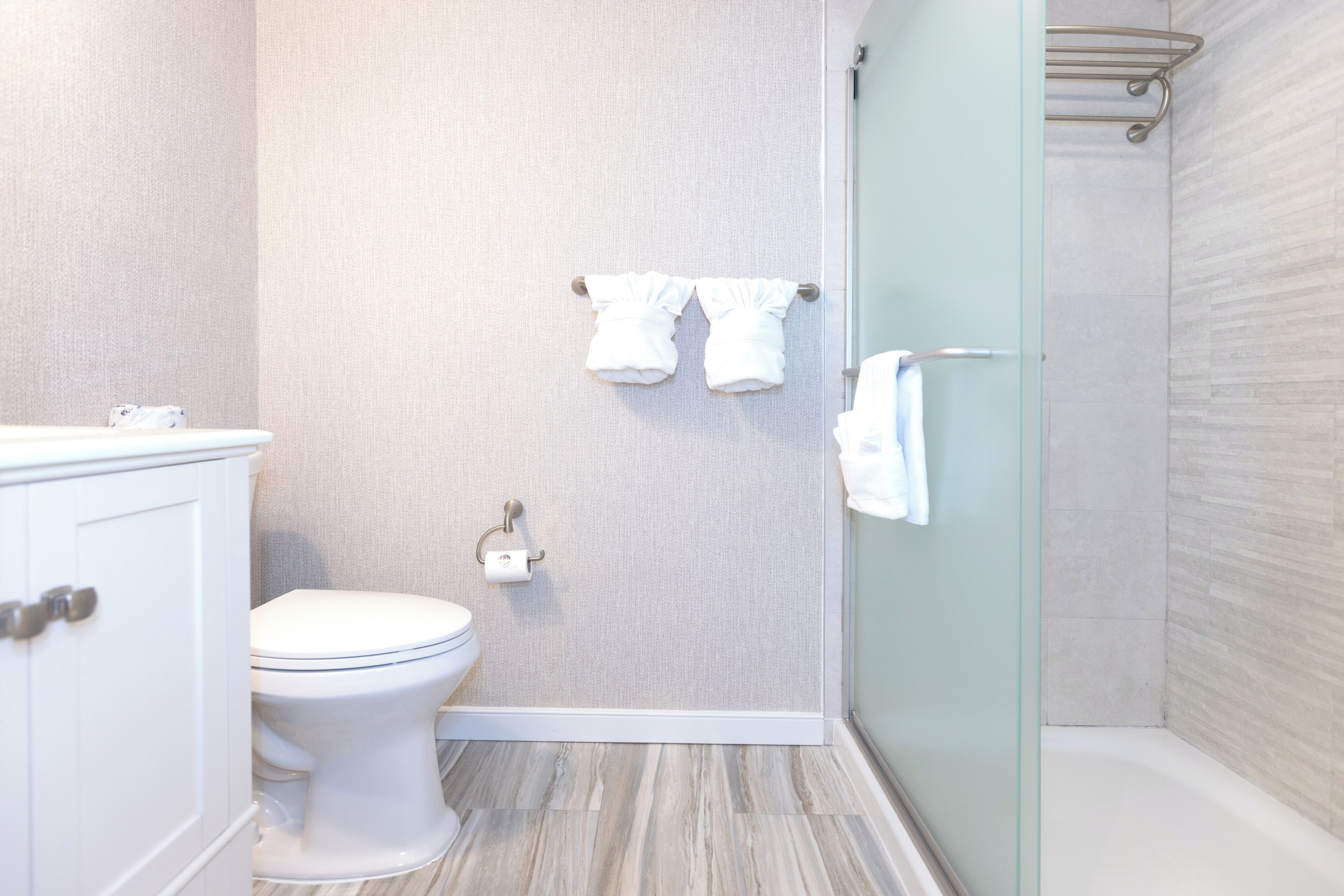 Un baño con inodoro, toallero y zona de ducha.