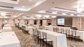 A conference room with long tables, chairs, and a presentation screen.