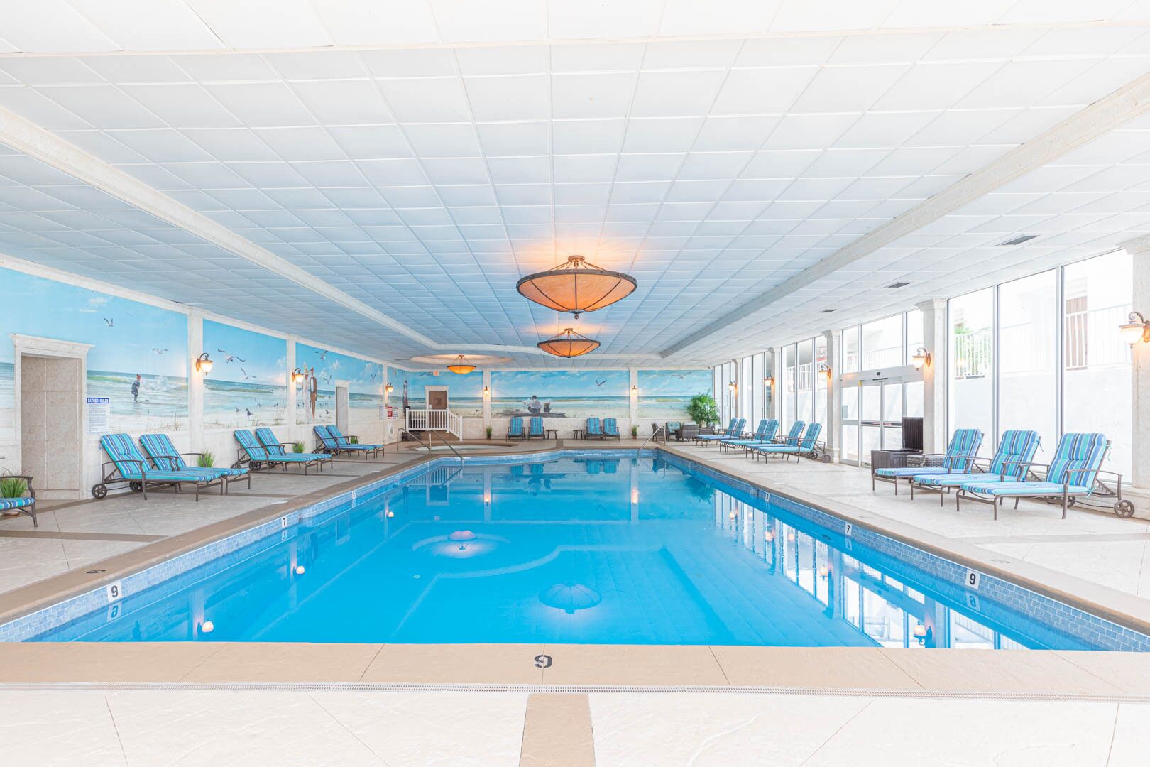 Ein Hallenbad mit Liegestühlen und einer Wandmalerei vom Strand.